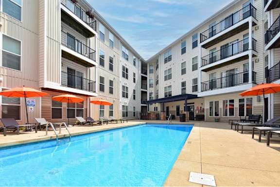 A large swimming pool is surrounded by apartment buildings.