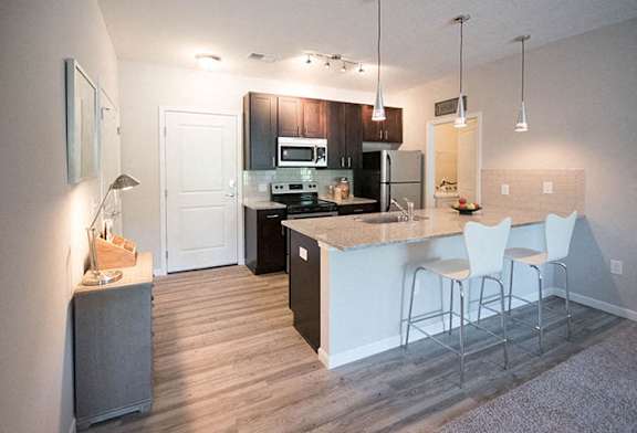 A kitchen with a bar area and white chairs.