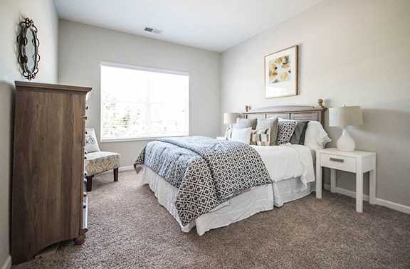 A bedroom with a large bed and a wooden armoire.