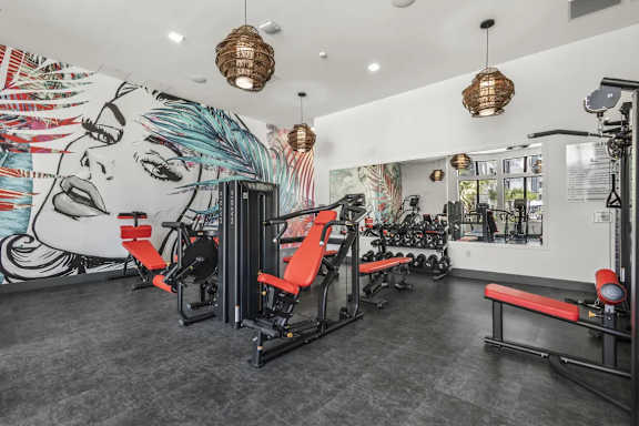 A gym with a wall mural and various exercise equipment.