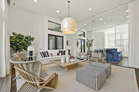 A modern living room with a striped ottoman and a wooden chair.