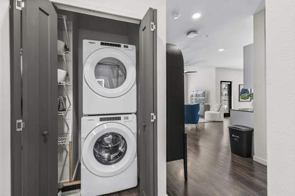 A modern laundry room with a washer and dryer built into a cabinet.