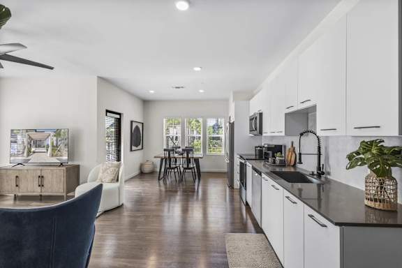 A modern kitchen with white cabinets and a dark blue chair.