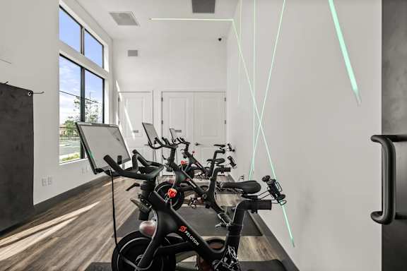 A bike is parked in a room with a white wall and a window.