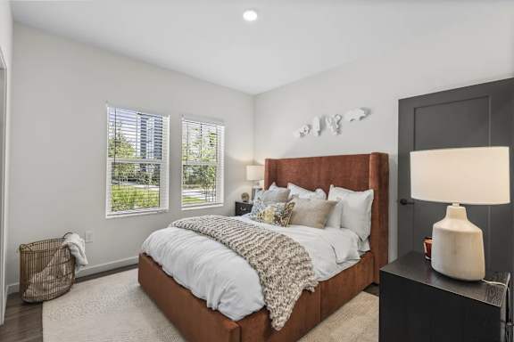 A bedroom with a large bed and a lamp on a side table.