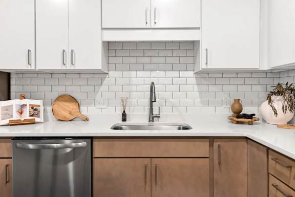 A kitchen with a stainless steel dishwasher and wooden cabinets.