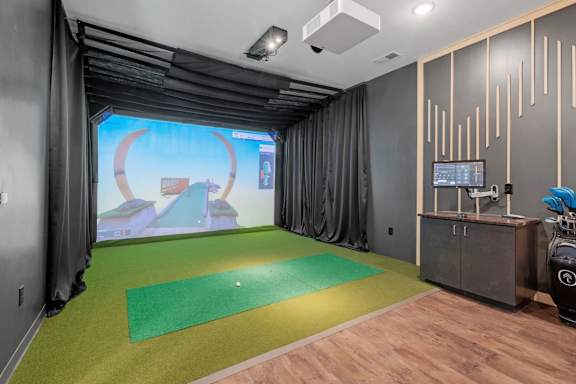 A room with a green mat and a screen showing a video game.