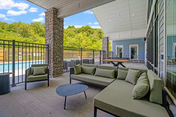 A patio with a table and chairs overlooking a pool.