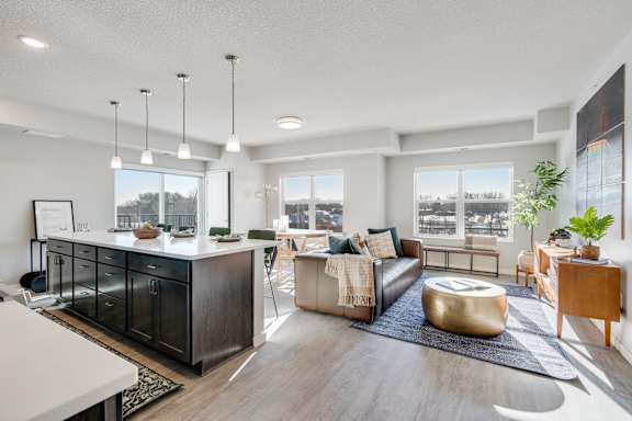 A modern living room with a kitchen area in the background.