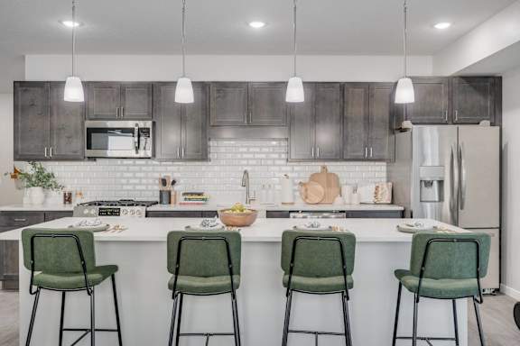 A kitchen with a white countertop and green barstools.