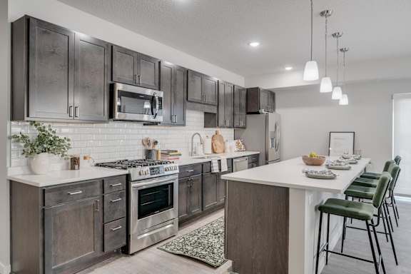 A modern kitchen with dark brown cabinets and stainless steel appliances.