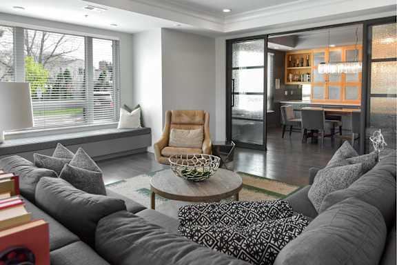 A living room with a grey couch and a wooden chair.