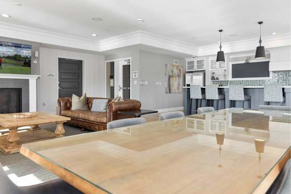 A modern living room with a glass table and leather couches.
