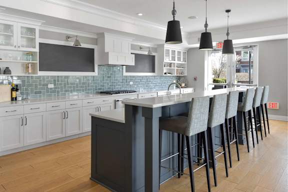 A kitchen with a long bar and chairs.