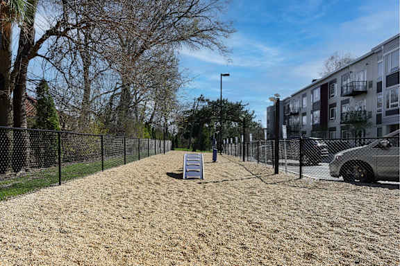 A sandy area with a bench and a fence in front of a building.