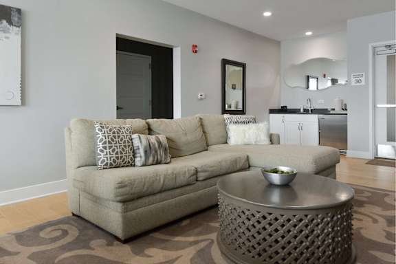 A grey couch with pillows sits in a living room with a coffee table in front of it.