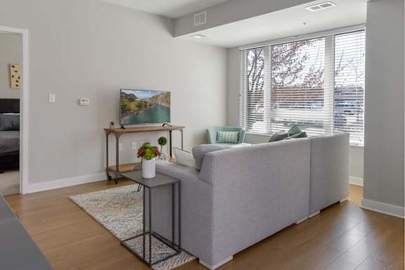 A living room with a grey couch and a painting on the wall.