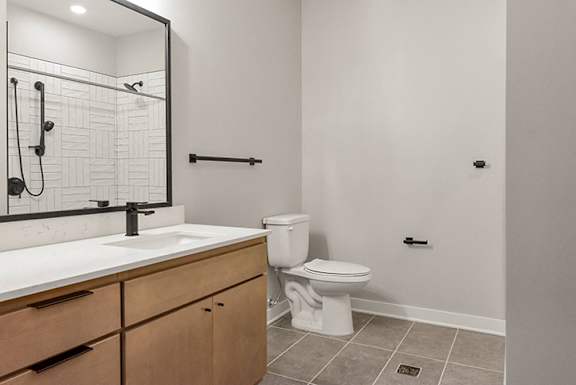 A white toilet sits in a bathroom next to a sink and a mirror.