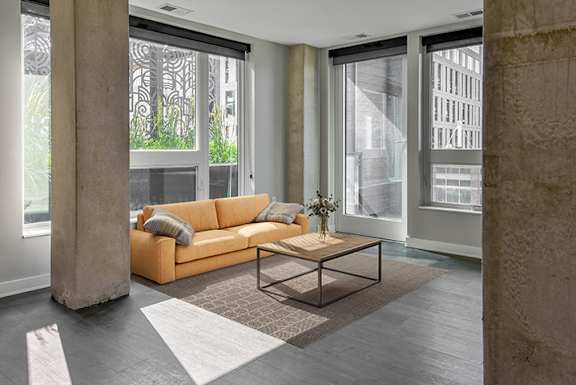 A living room with a yellow sofa and a glass table.