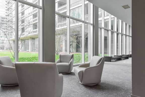 Armchairs next to panel of large windows at Optima Old Orchard Woods luxury apartments in Chicago Suburbs
