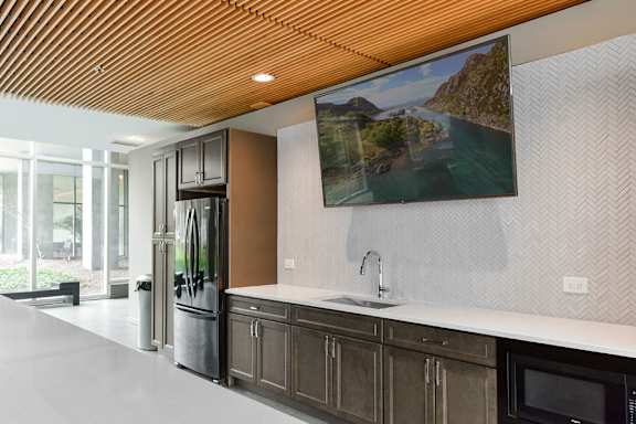 A modern kitchen with a wooden ceiling and a painting of a river on the wall.
