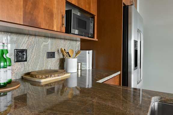 A kitchen with a brown counter top and a stainless steel refrigerator.