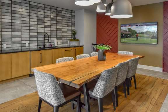 A modern dining room with a wooden table and grey chairs.