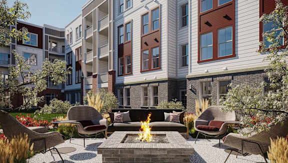 A fire pit sits in the middle of a patio surrounded by chairs and plants.