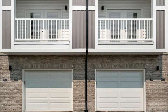 A building with two garage doors and a balcony.