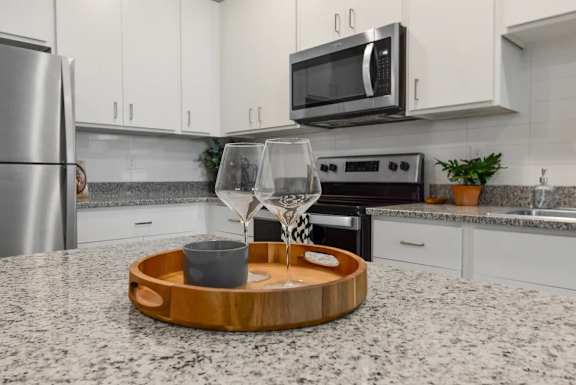 A modern kitchen with a granite countertop and stainless steel appliances.