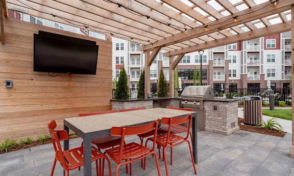A patio with a table and chairs and a TV on the wall.