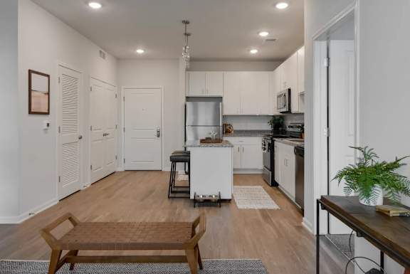 A modern kitchen with a white refrigerator, stove, and oven, and a wooden dining table with chairs.