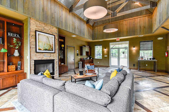 A large grey couch sits in the middle of a spacious room with a fireplace.