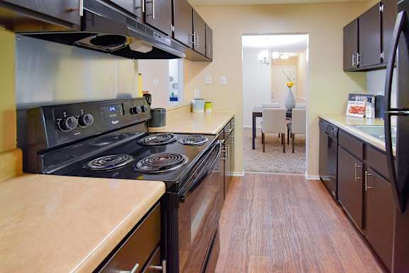 A kitchen with a black stove top oven and black cabinets.
