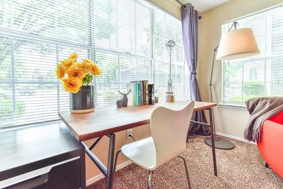 A room with a table, chairs, and a vase of flowers.