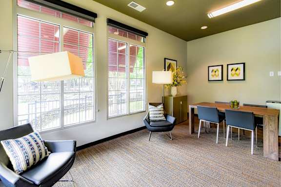A living room with a black chair and a table with chairs around it.