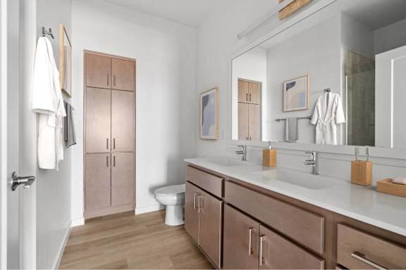 A bathroom with a toilet, sink, and cabinets.