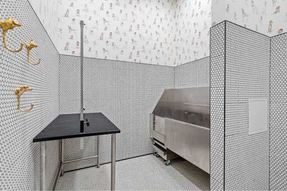 A black table with a metal stand in a room with a wallpapered wall.