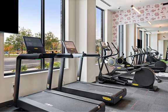 A gym with treadmills, exercise bikes, and a television.