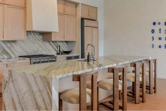 A kitchen with a marble countertop and wooden bar stools.