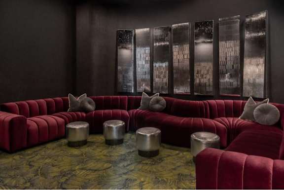 A room with a red couch and a green floor.