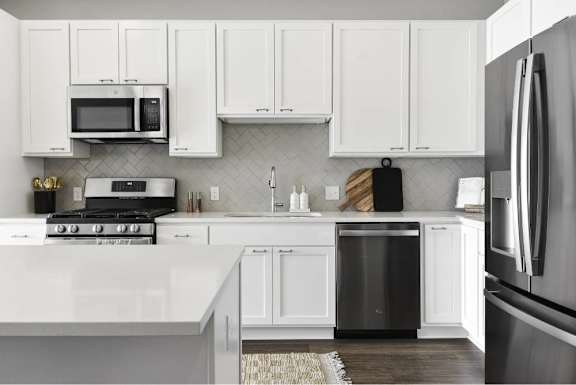 A modern kitchen with white cabinets and appliances.
