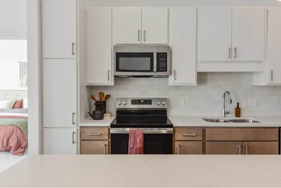 A kitchen with a stove, oven, microwave, and cabinets.