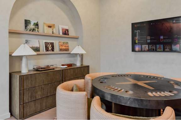 A modern living room with a round table and a flat screen TV mounted on the wall.