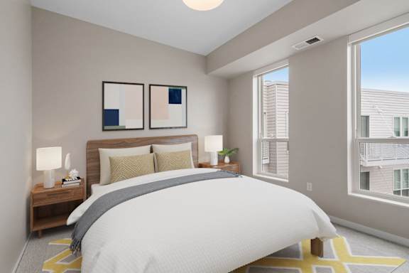 A bedroom with a large bed and two lamps on a nightstand.
