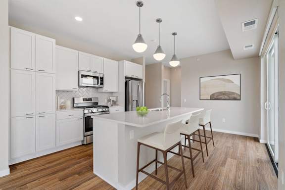A kitchen with white cabinets and a large island with chairs.