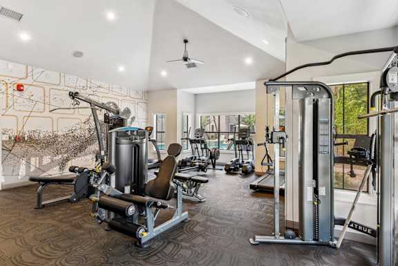 A gym with a variety of equipment including a weight bench, a leg press machine, and a cable machine.