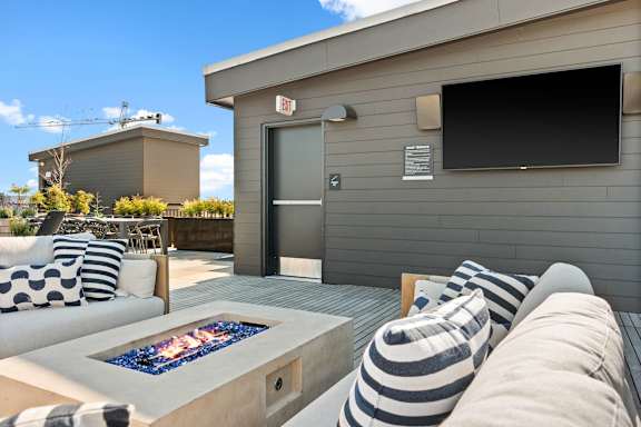 A modern outdoor seating area with a fire pit and striped cushions.