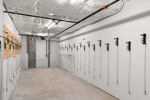 A long hallway with white walls and black pipes on the wall.
