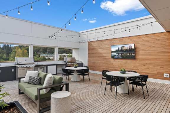 A patio with a table, chairs, and a couch with a view of trees.